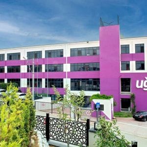 Mor şeritli, “Uğur Okulları” tabelalı üç katlı okul binası ve bahçesi